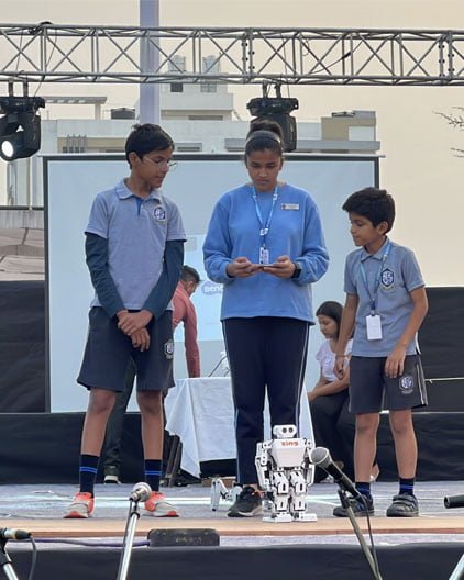 A group of children standing on stage with a robot.