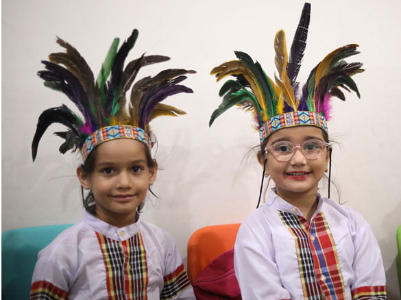 Two students wearing traditional tribal headgear for an art project