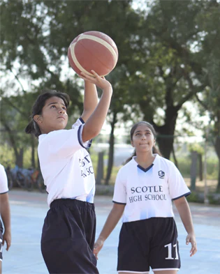 A group of girls in school uniforms practicing basketball at Scotle High School.