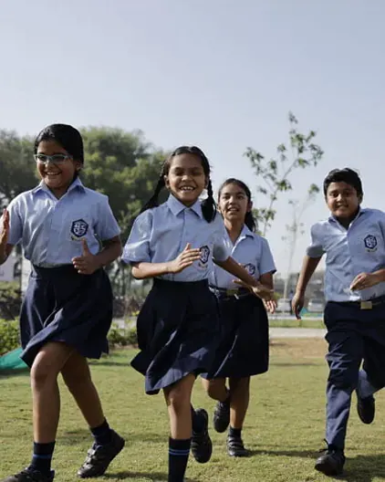 A group of school children running on a grassy field.